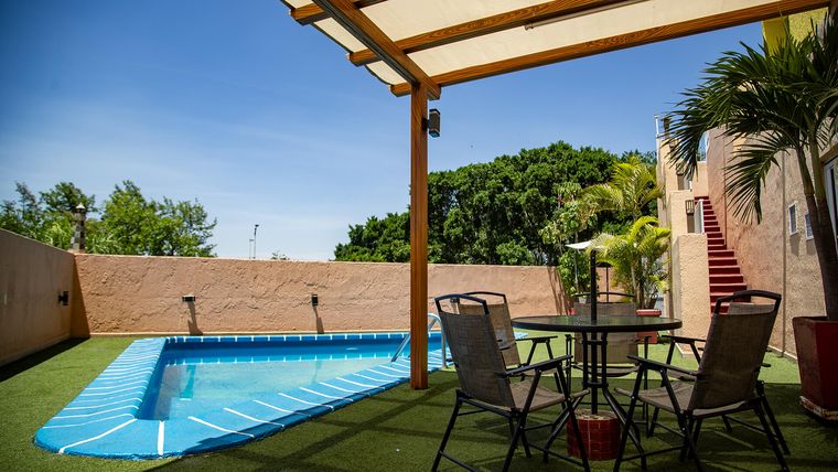 Alberca al aire libre con pérgola y jardín